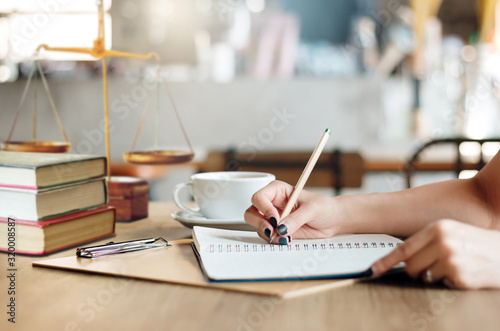 Close up of hand female lawyer writing on notebook while she working on desk