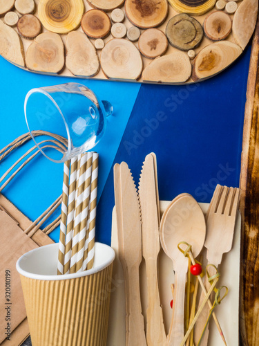 Disposable wooden cutlery and paper bag on trendy blue color background, cutlery, recycling and eco friendly concept, plastic-free alternatives zero waste environmental protection