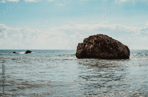 Single rock in the sea during sunny day, copy space