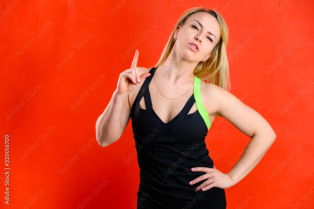 Photo of a beautiful pretty slim woman blonde sportswoman in a tracksuit on a red background. The concept of fashionable fitness. Standing in different poses with emotions and a smile. Photo of a beautiful pretty slim woman blonde sportswoman in a tracksuit on a red background. The concept of fashionable fitness. Standing in different poses with emotions and a smile.