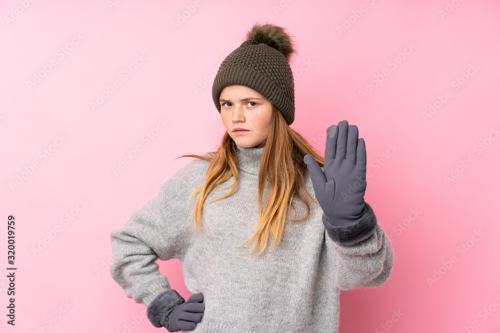 Ukrainian teenager girl with winter hat over isolated pink background making stop gesture with her hand Ukrainian teenager girl with winter hat over isolated pink background making stop gesture with her hand