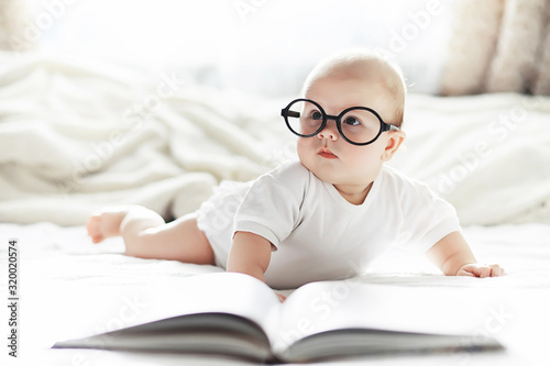 A newborn baby is lying on a soft bed in glasses.
