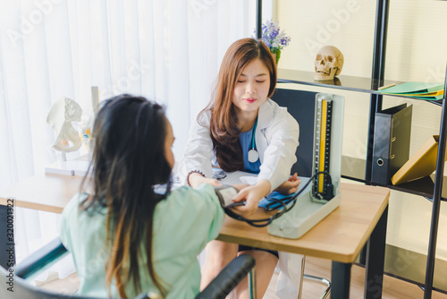 Asian beautiful female doctor is measuring the blood pressure of the patient.