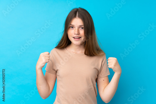 Ukrainian teenager girl over isolated blue background celebrating a victory in winner position