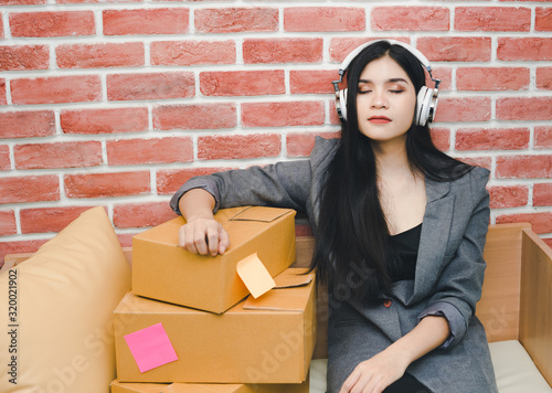 Asian business woman As a small business owner, start up a job. She is relaxing from checking the stock by listening to music. Sme concept.