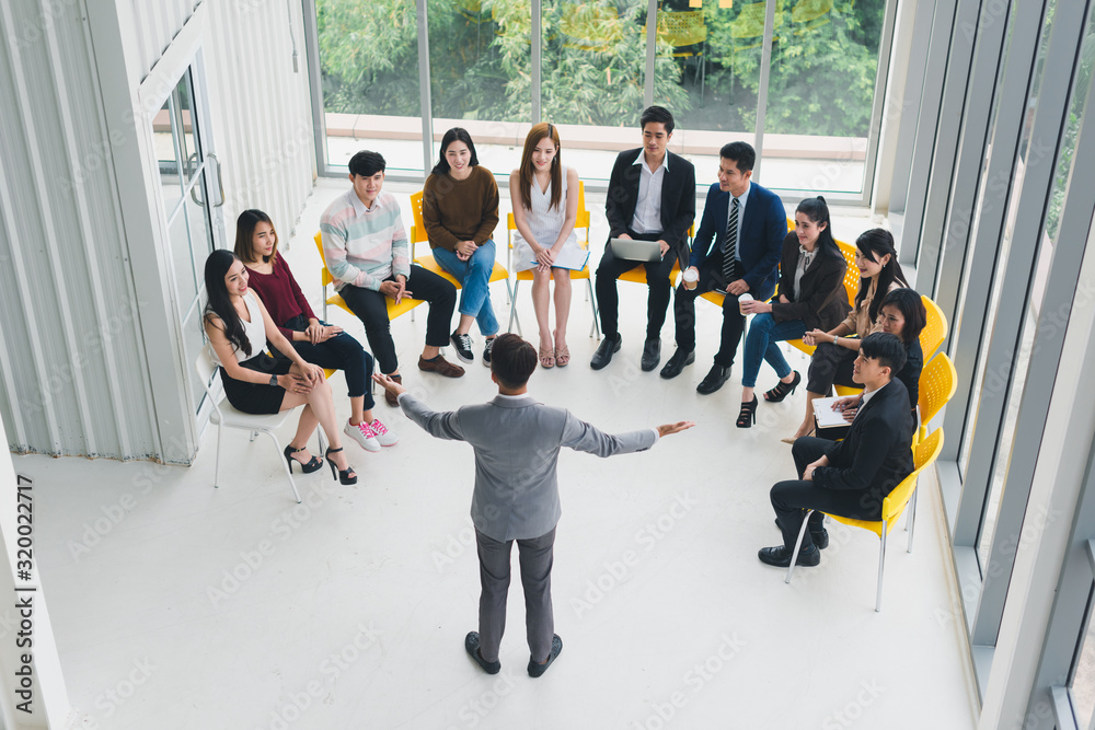Obraz premium Asian Speaker male is speaking at seminars and workshops to the people in the meeting. By the participants of the seminar and training sitting round a semicircle. Top view.