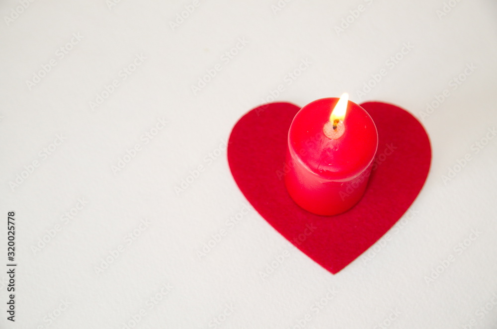 Valentine's Day. On a white background is a red candle and a felt felt heart. Valentine's Day. On a white background is a red candle and a felt felt heart.