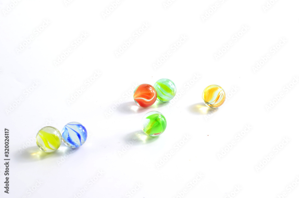 Colored glass balls spread over the white background of the room Colored glass balls spread over the white background of the room