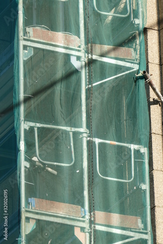 Grüne Abdeckplane, Baustelle, Baugerüst, Hausfassade photo