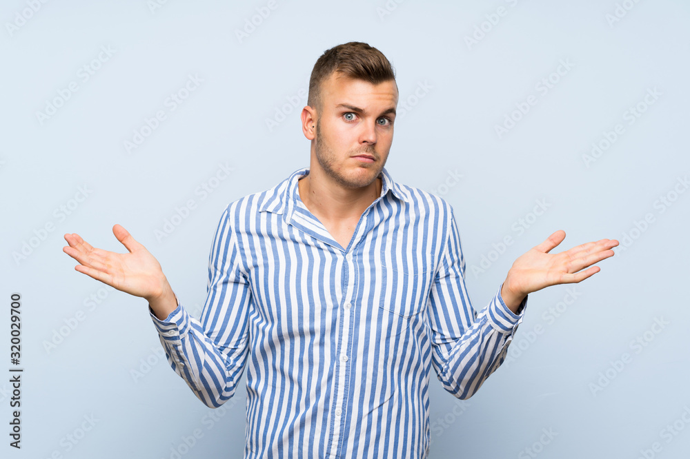 Fototapeta premium Young handsome blonde man over isolated blue background making doubts gesture