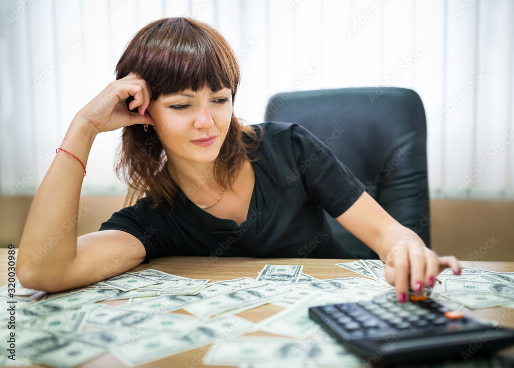 Happy young businesswoman counts her income in office Happy young businesswoman counts her income in office
