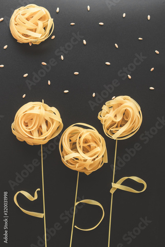 uncooced italian pasta fettuccine. Pasta flowers on a star sky black background photo