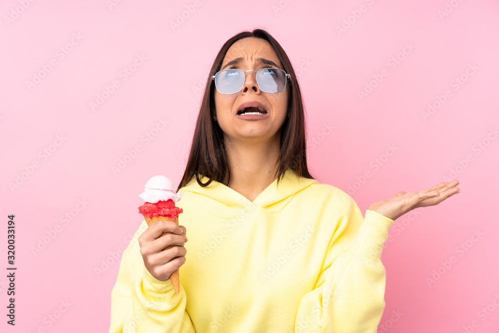 Young brunette girl holding a cornet ice cream over isolated pink background frustrated by a bad situation Young brunette girl holding a cornet ice cream over isolated pink background frustrated by a bad situation