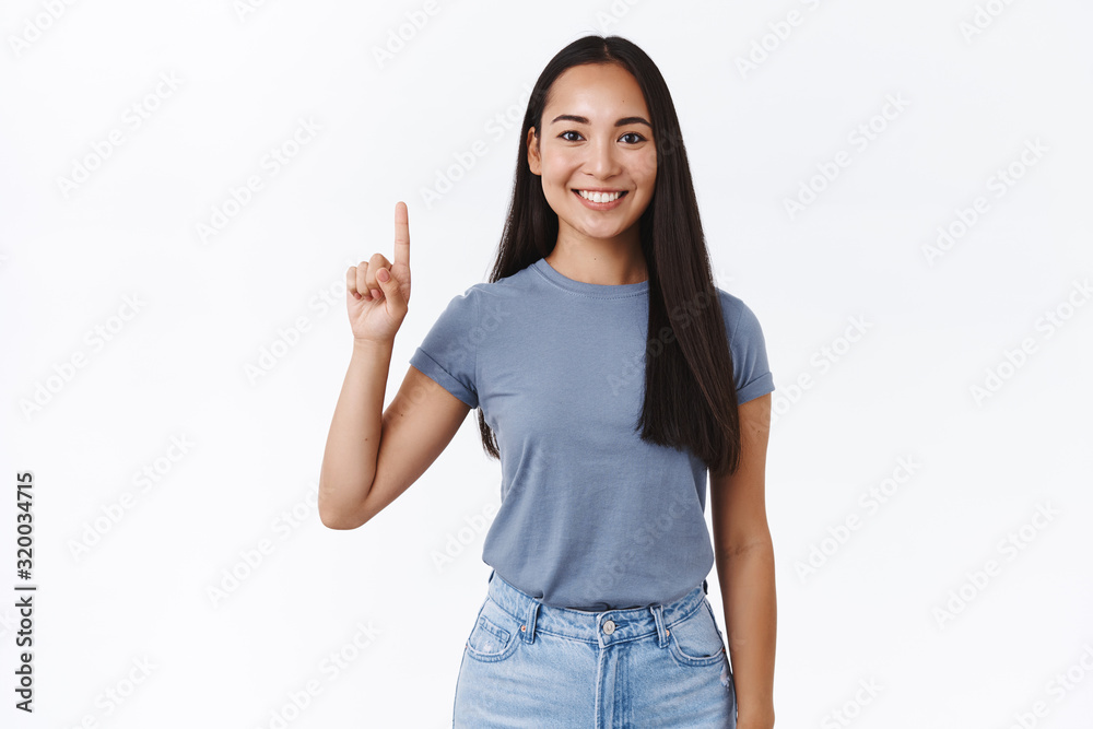 Portrait of cheerful, asian 20s girl in casual t-shirt, pointing fingers up, showing number one, smiling carefree, give advice, promote product, indicating what link click, white background Portrait of cheerful, asian 20s girl in casual t-shirt, pointing fingers up, showing number one, smiling carefree, give advice, promote product, indicating what link click, white background