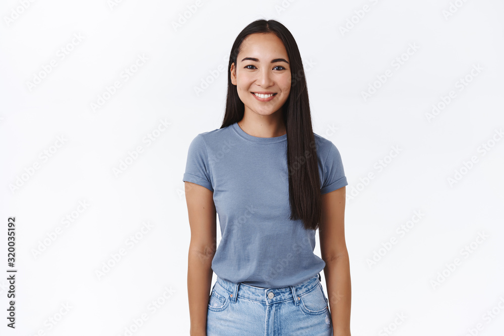 Portrait cheerful smiling asian woman with long dark hair, wear t-shirt and jeans, grinning joyfully, casual pose with arms down, express joy, carefree, relaxed emotions, standing white background Portrait cheerful smiling asian woman with long dark hair, wear t-shirt and jeans, grinning joyfully, casual pose with arms down, express joy, carefree, relaxed emotions, standing white background