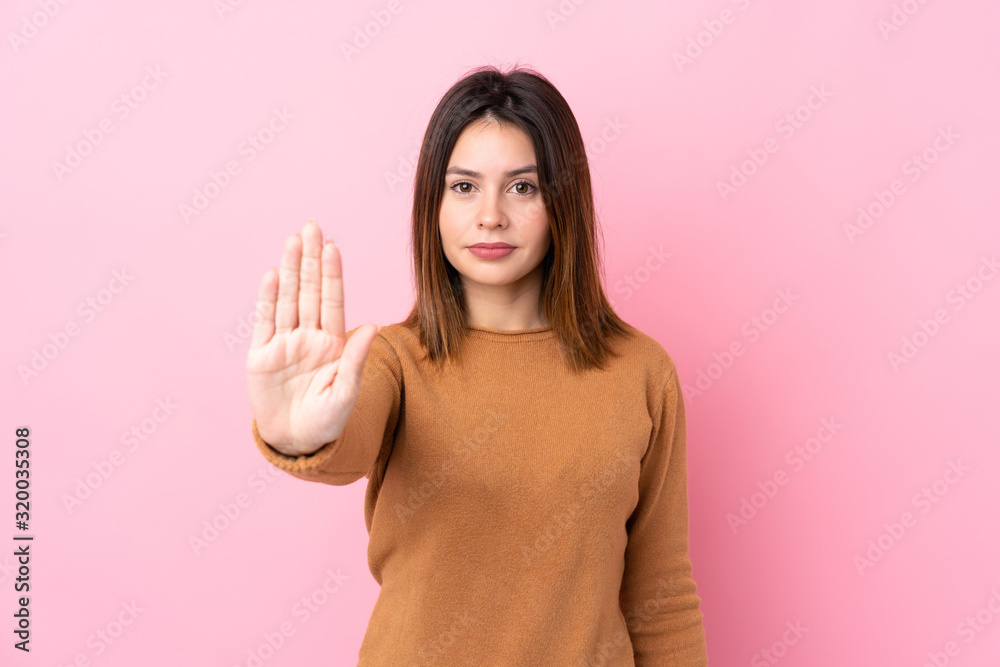 Young woman over isolated pink background making stop gesture - obrazy, fototapety, plakaty 