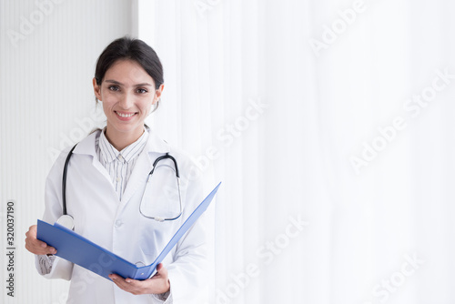 A doctor woman has to work with reading the report at the hospital with smiling and happiness.