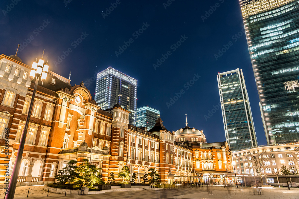 東京都千代田区丸の内の夜のライトアップした東京駅と高層ビル群
