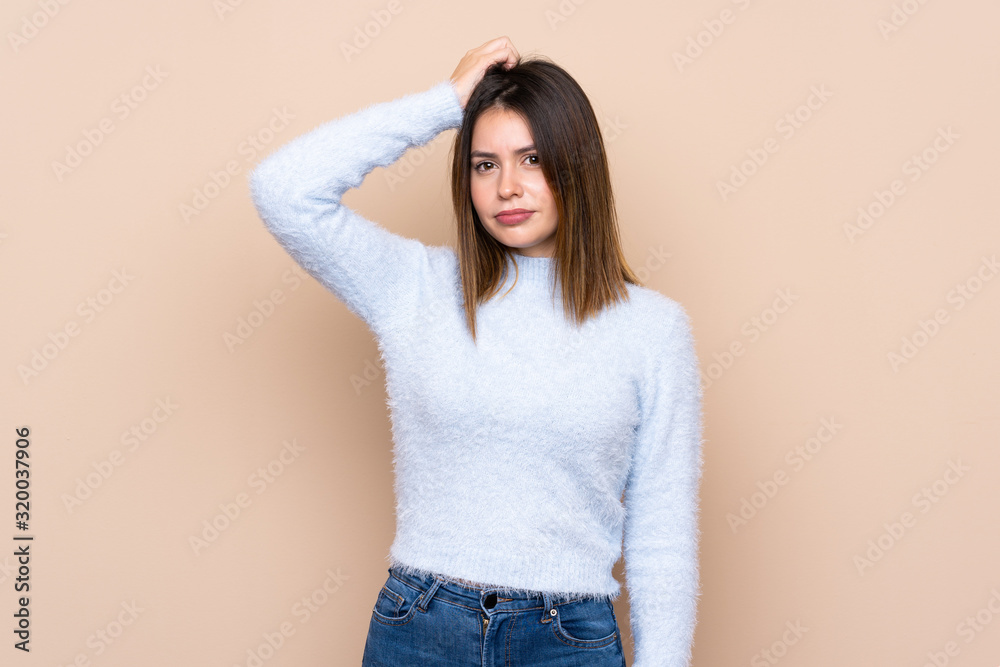 Young woman over isolated background having doubts while scratching head Young woman over isolated background having doubts while scratching head