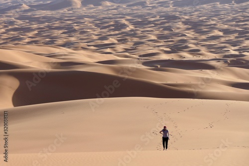 Woman walking on sand dunes in Sahara  Morocco  Africa
