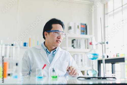 Asian scientists are preparing chemicals for testing and analysis in the laboratory. Scientists clear glasses and white shirts. Science and Chemistry Concept