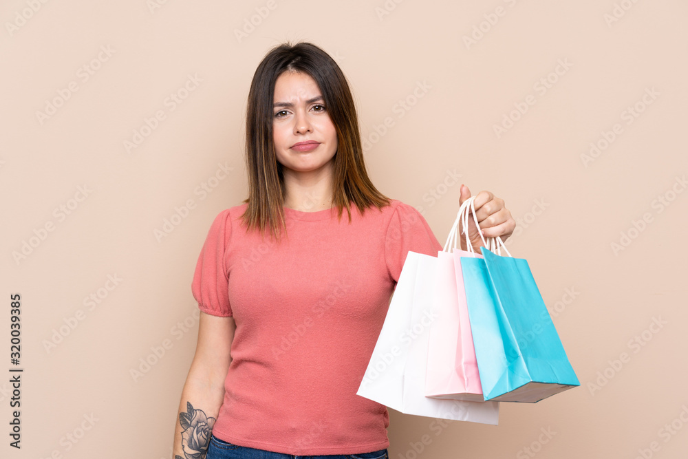 Young woman with shopping bag over isolated background with sad expression
