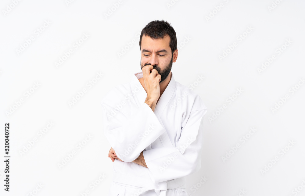 Young man doing karate over isolated white background having doubts Young man doing karate over isolated white background having doubts