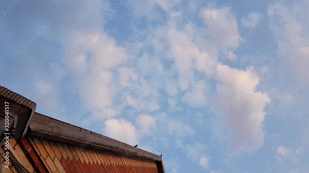 blue sky with white clouds, the roof of the house with three sparrow birds