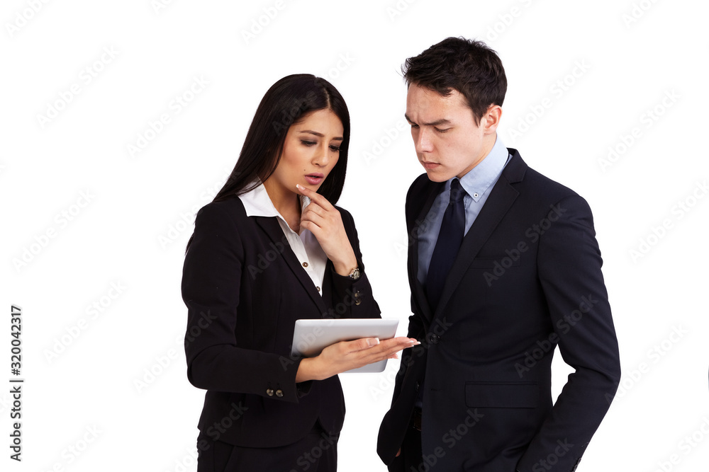 A young female business woman is holding a tablet while a young female business man is looking at it. He is looking serious and stressed.