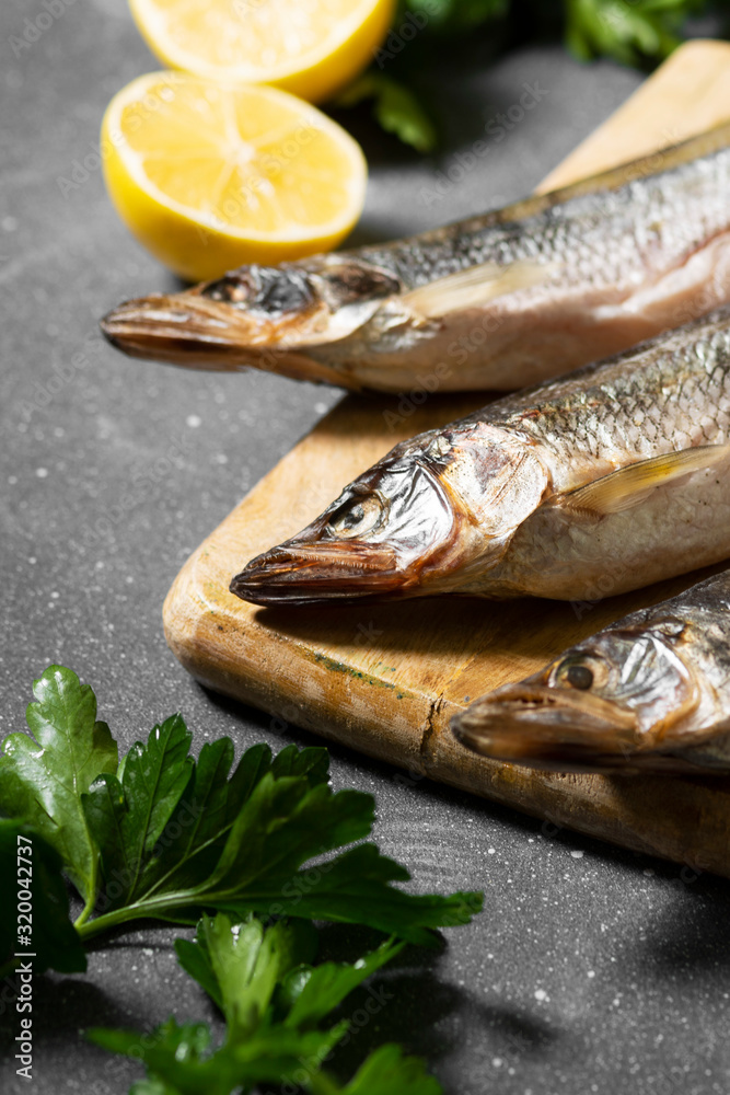 Smoked or dried smelt fish on a wooden Board on a gray kitchen table. Top view with space for text