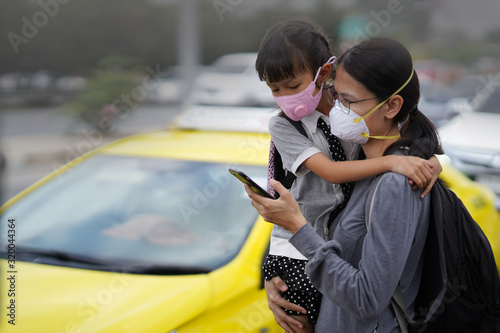 Asian woman wearing N95 mask to prevent for PM2.5 beside the street/ road