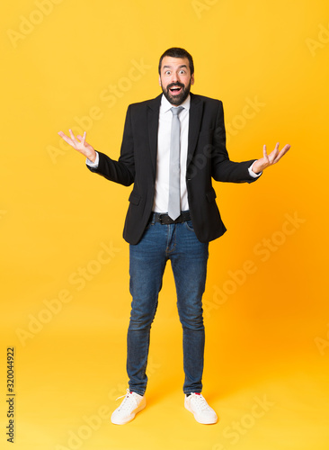 Full-length shot of business man over isolated yellow background with shocked facial expression
