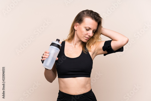 Blonde sport woman over isolated background with sports water bottle