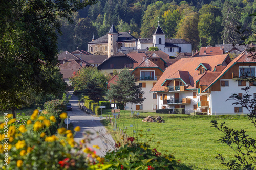 Beautiful view of the Giez village: flowers in the foreground, the road and houses among the greenery and the castle on top, Savoy. Best villages of France