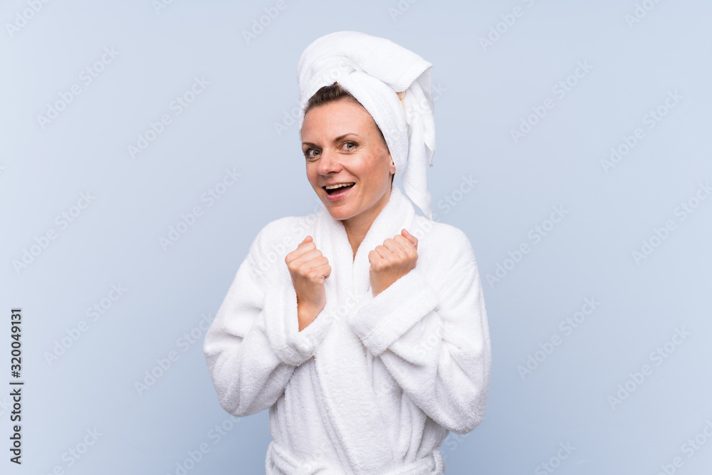 Woman in bathrobe over isolated blue background celebrating a victory Woman in bathrobe over isolated blue background celebrating a victory