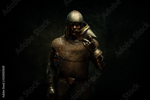 Portrait of a knight in armor holding his helmet in his hand