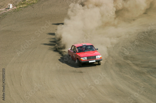 Rally car skidding on a dusty gravel road
