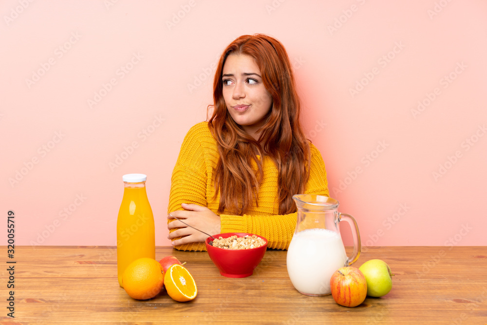 Teenager redhead girl having breakfast in a table thinking an idea Teenager redhead girl having breakfast in a table thinking an idea