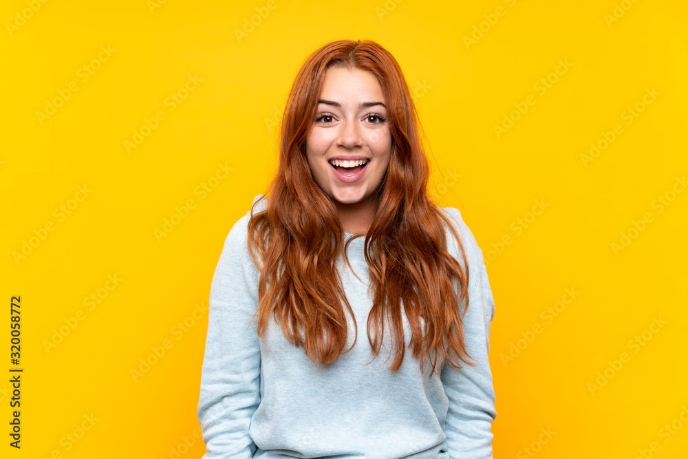 Teenager redhead girl over isolated yellow background with surprise facial expression Teenager redhead girl over isolated yellow background with surprise facial expression