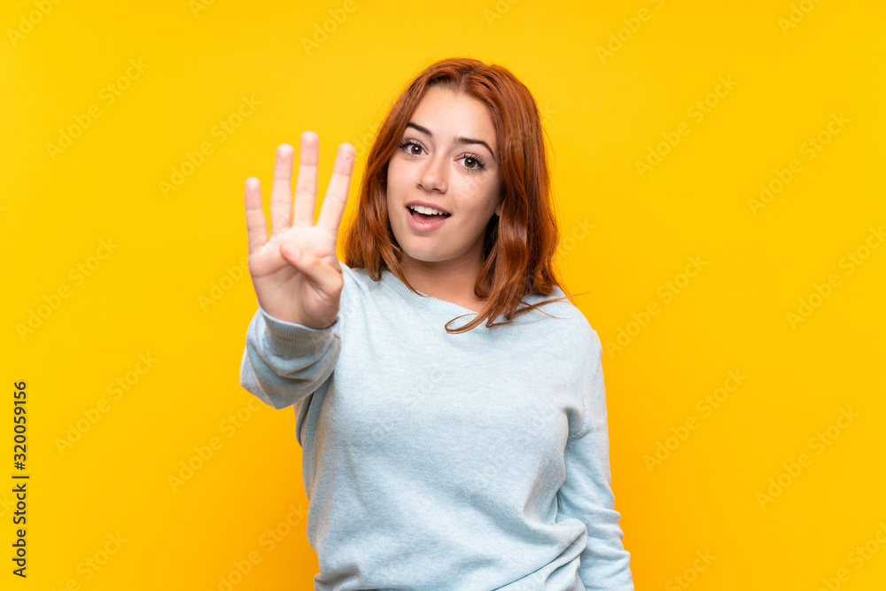 Teenager redhead girl over isolated yellow background happy and counting four with fingers