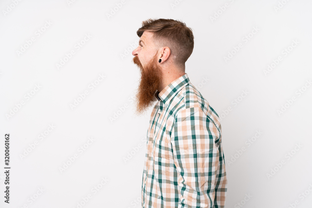 Redhead man with long beard over isolated white background laughing in lateral position Redhead man with long beard over isolated white background laughing in lateral position