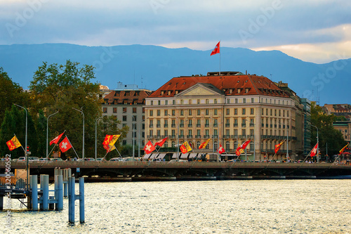 Sunset at Geneva Lake and Mont-Blanc bridge with many Swiss flags, Geneva of Switzerland. People on the background