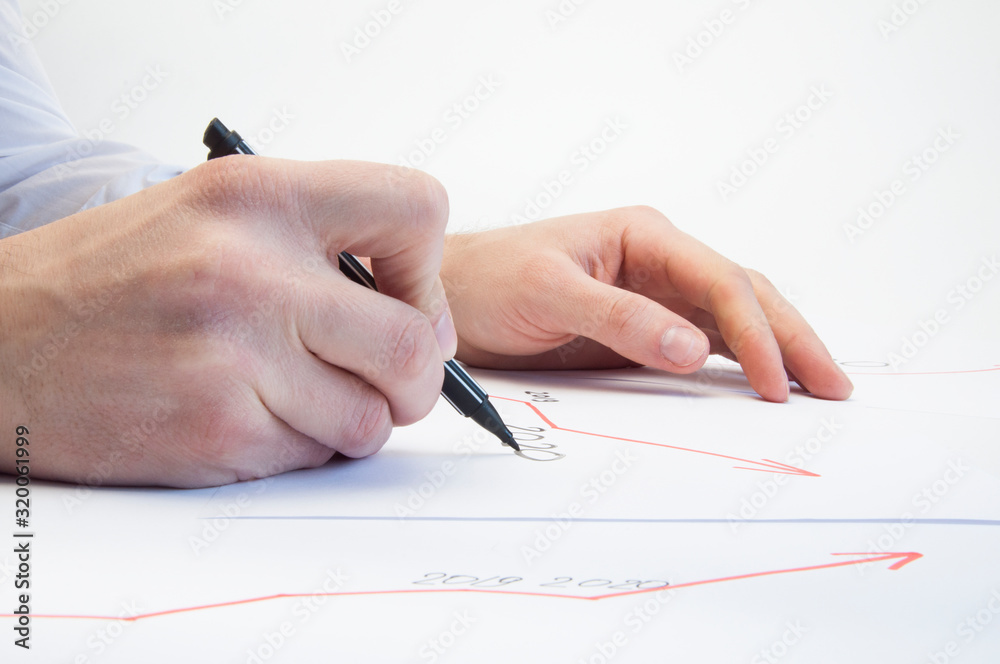 Hands of a male businessman write on a white sheet a growth graph. Growth arrow. On white background Hands of a male businessman write on a white sheet a growth graph. Growth arrow. On white background