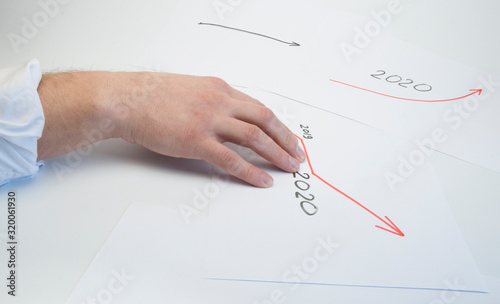 Hands of a male businessman write on a white sheet a growth graph. Growth arrow. On white background