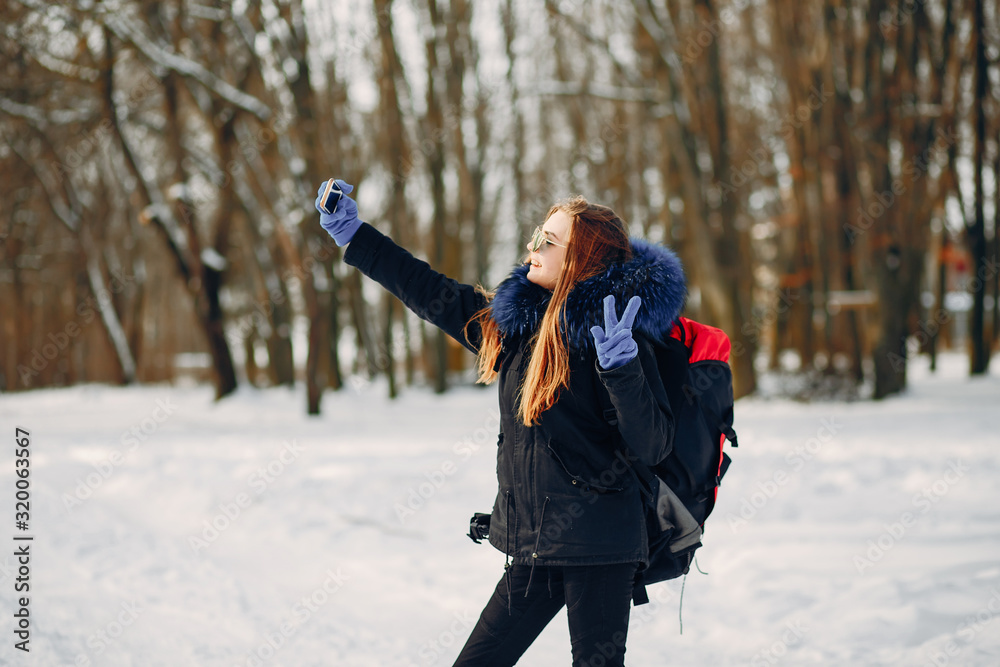 young and pretty girl are walking in the winter snow-covered forest with backpack
