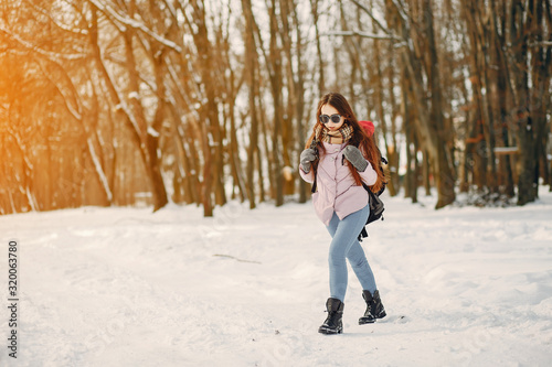 young and pretty girl are walking in the winter snow-covered forest with backpack