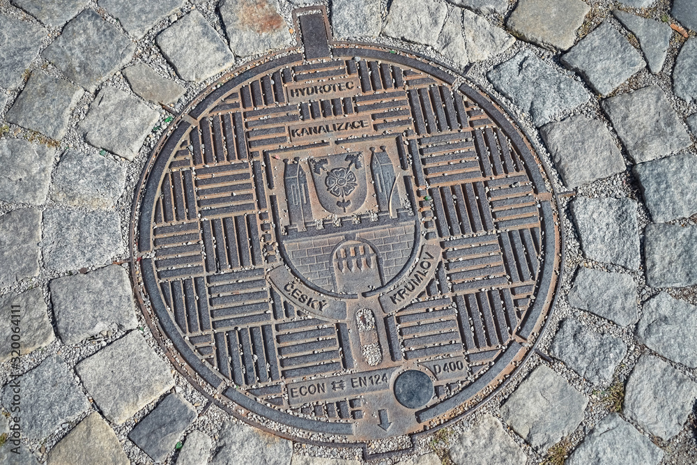 Czech sewer metal hatch with a pattern on the street with paving stones
