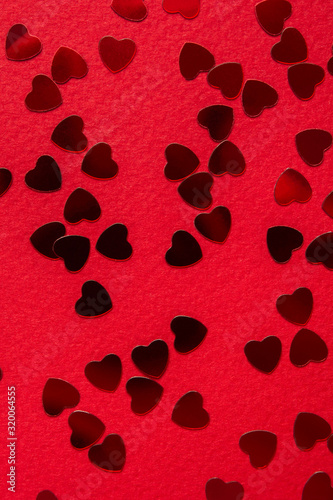Red heart shape confetti over red background. Top view