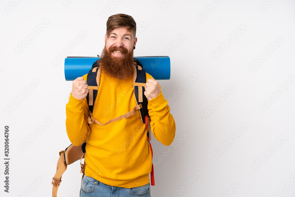 Young mountaineer man with a big backpack over isolated white background celebrating a victory Young mountaineer man with a big backpack over isolated white background celebrating a victory