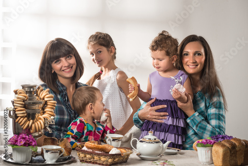 Young cute caring mother pours tea to her little cute son during a tea party with pastries. The concept of traditional Russian cuisine